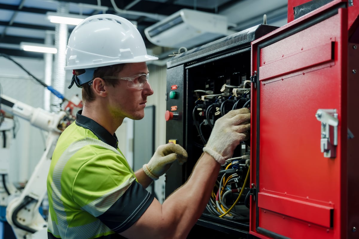 engineer performing electrical inspection and maintenance on industrial control cabinet