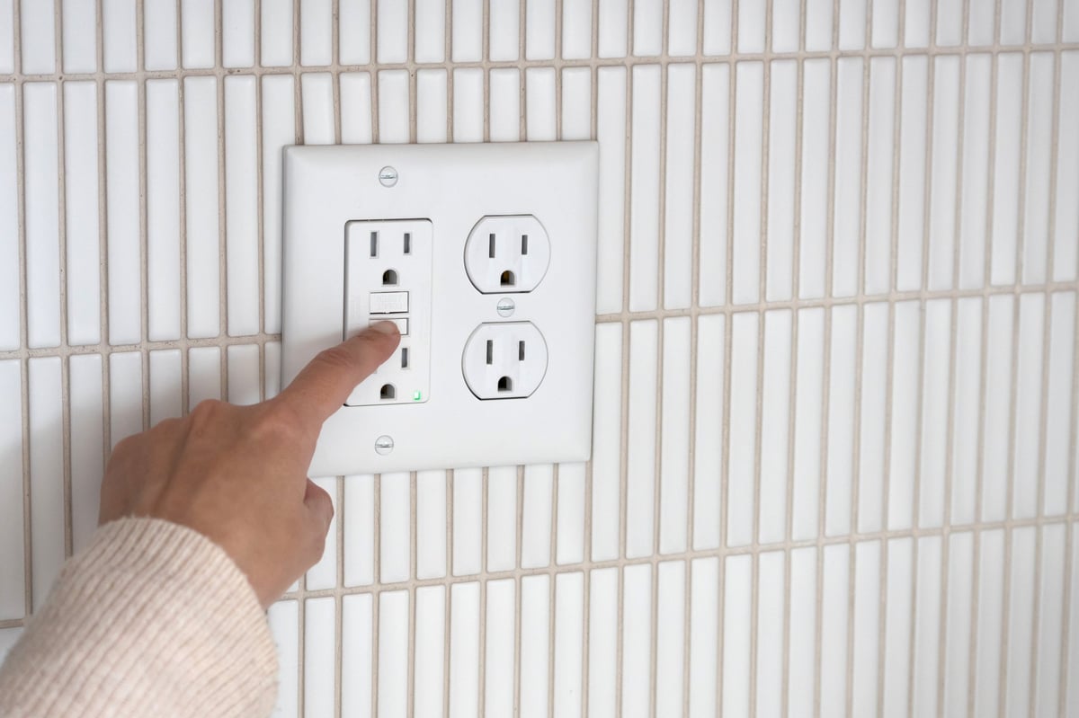 Person pressing the test button on the GFCI outlet