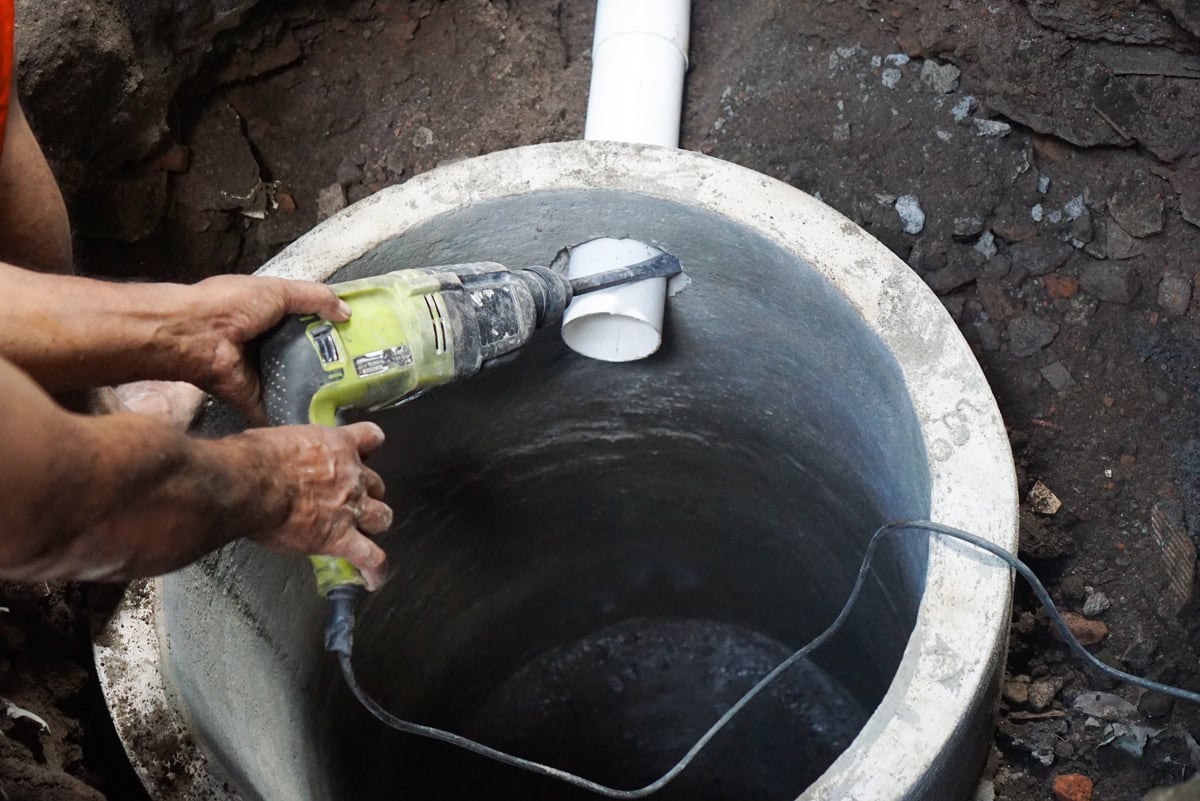 The installation of a concrete septic tank riser.