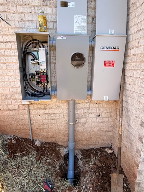 Generac backup generator system mounted on brick wall with electrical components and PVC conduit pipe below