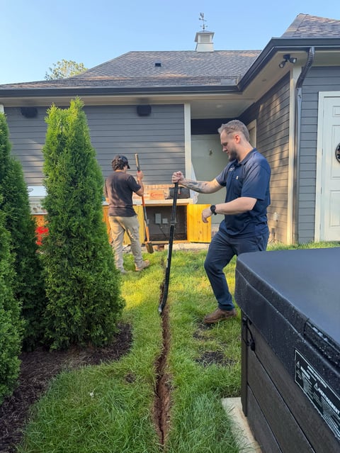Man and child cooking together on an outdoor grill in a backyard next to a house