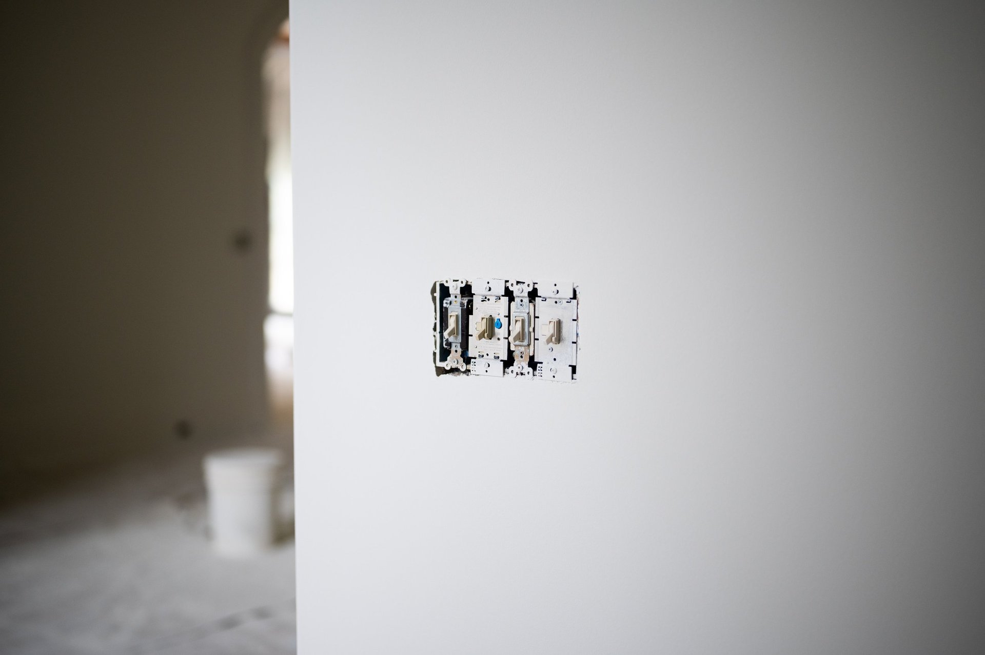 Electrical outlet mounted on a white wall in an empty, minimalist room with concrete flooring
