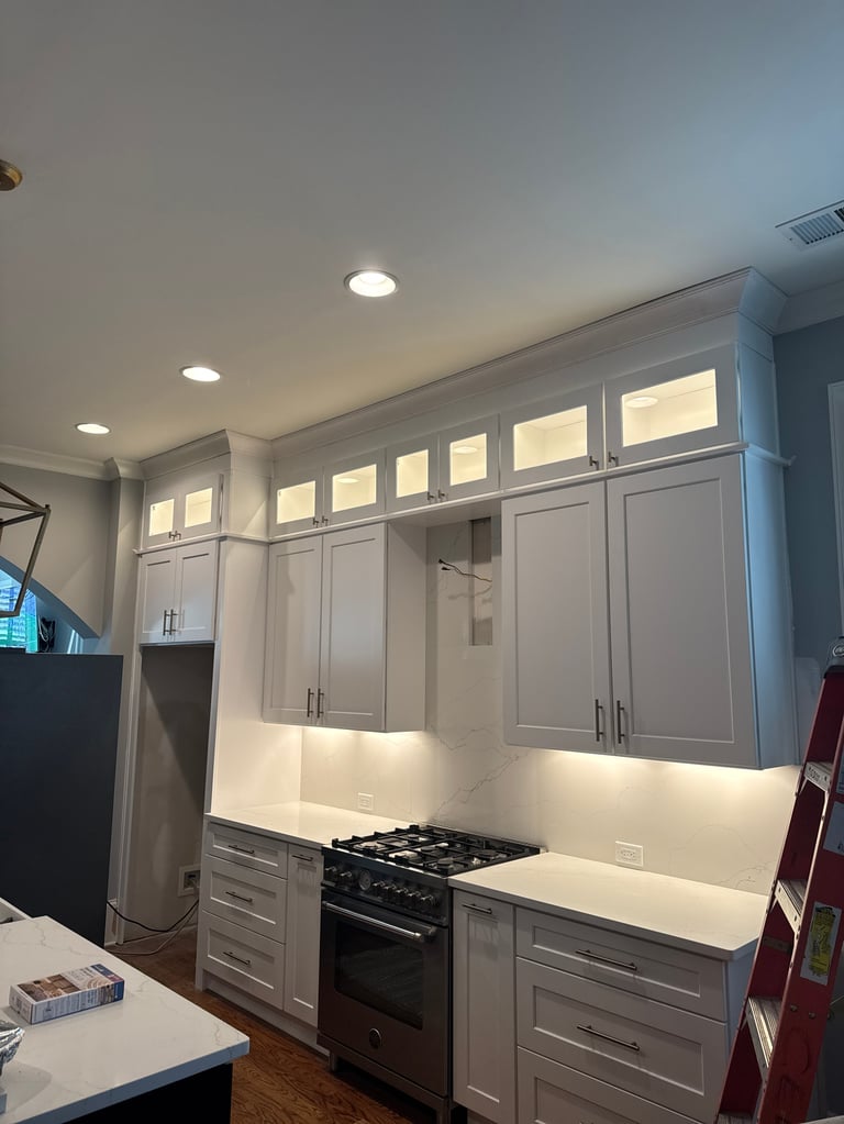 Modern kitchen with gray cabinetry, black range stove, white countertop, and glass-front upper cabinets with recessed lighting