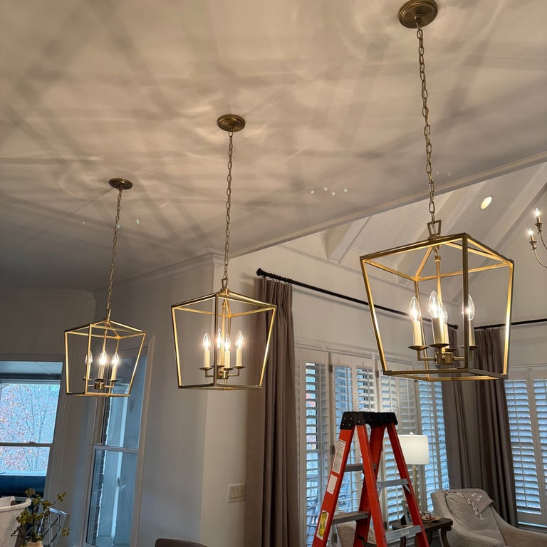Three hanging pendant lights with geometric frames installed from a white ceiling in a modern interior space