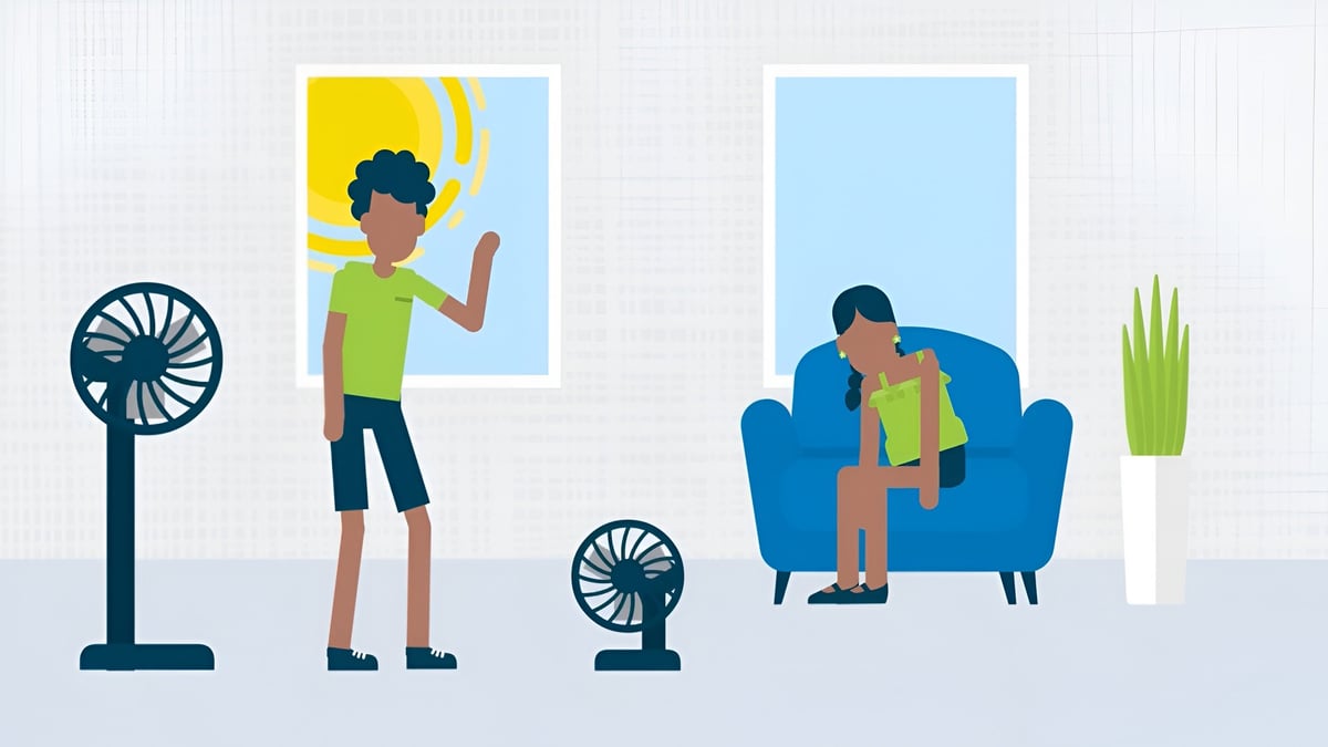 Person standing near a fan and holding artwork, another person sitting on a blue couch with a small fan, in a living room setting