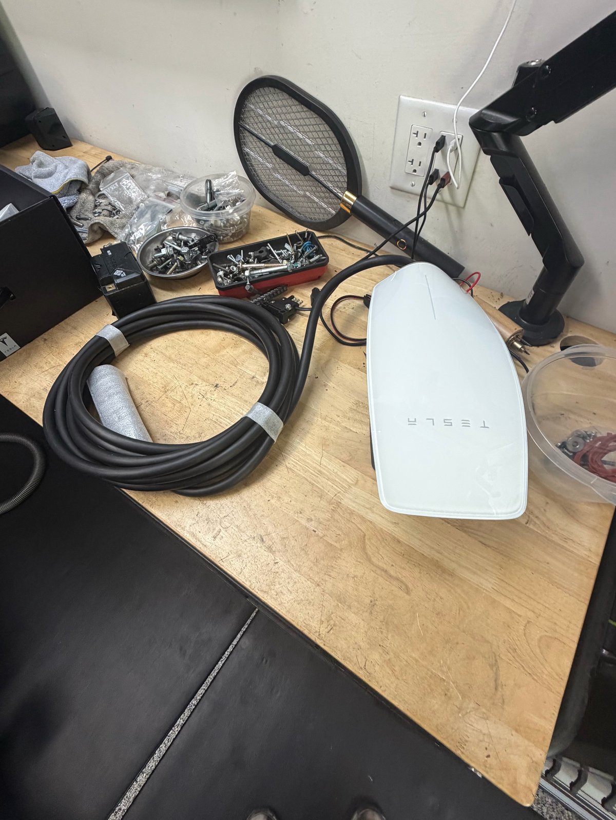 White router with various cables, a butterfly net, and equipment scattered on a wooden desk surface