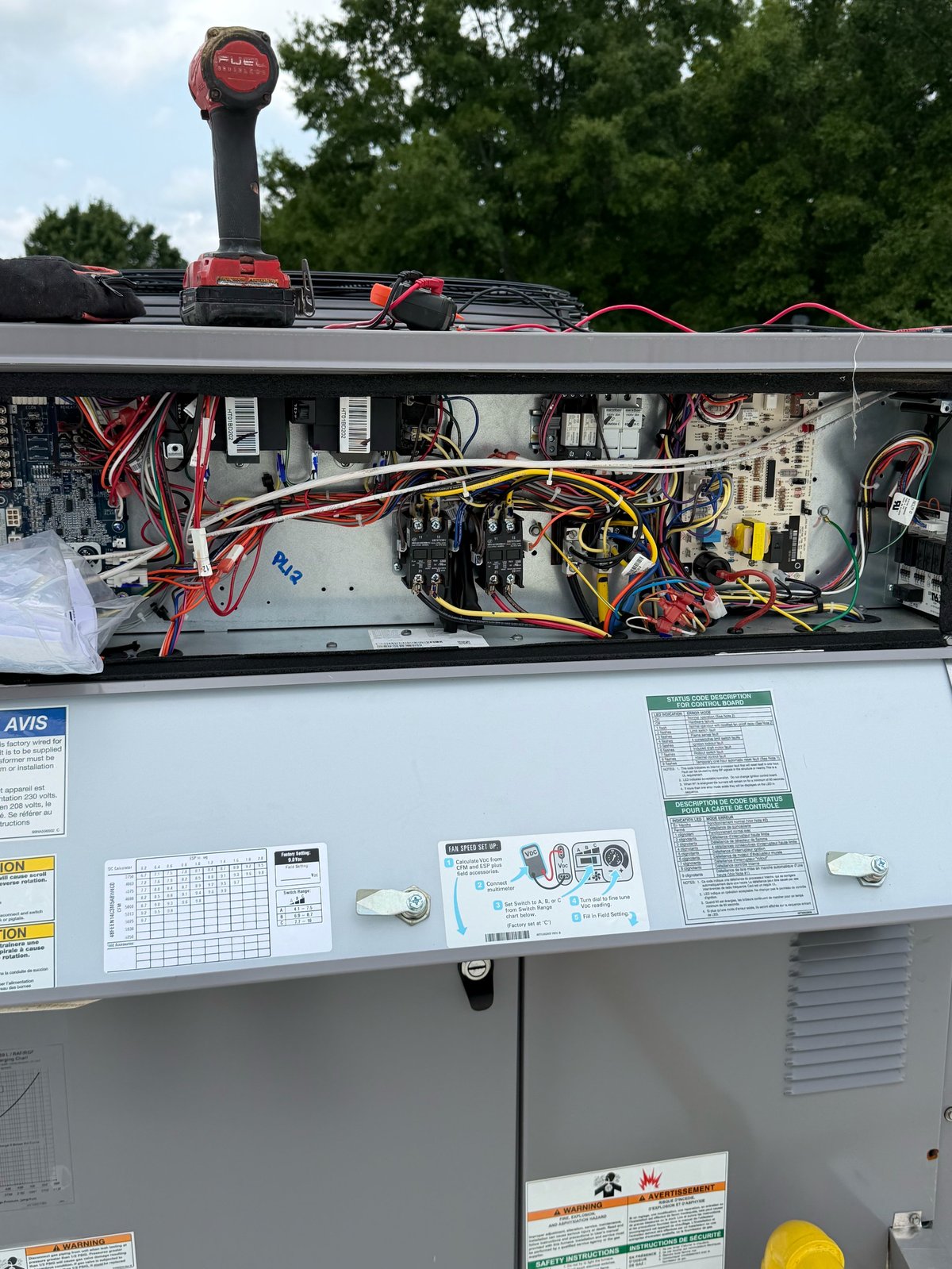 Interior view of electrical equipment panel with red and black wiring, circuit breakers, and control components mounted on an HVAC or utility unit