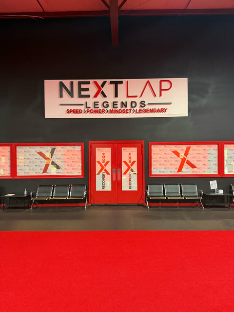 Red and black storefront for NextLap Legends with signage reading Speed Power Mindset Legendary, featuring red entrance doors and metal benches