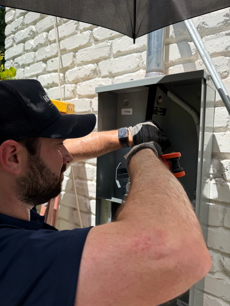 Electrician installing or repairing a black electrical panel on a brick wall under an umbrella
